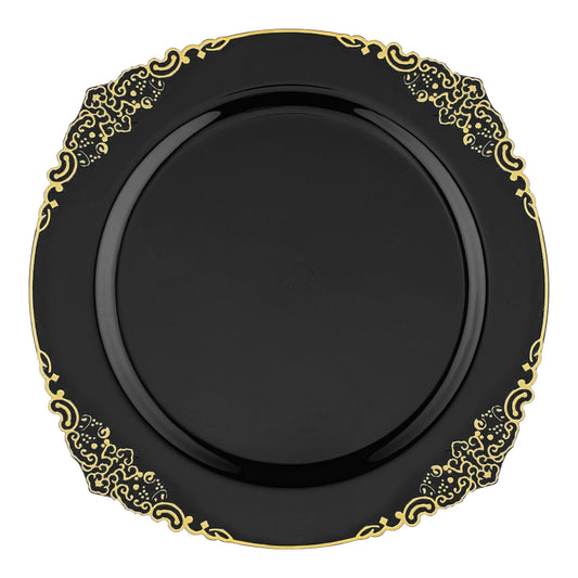 A round, black plate with intricate gold detailing along the scalloped edges, featuring elegant and ornate patterns that give it a luxurious and sophisticated appearance. These Black with Gold Fancy Round Plastic Dinner Plates (10.25”) are perfect for any upscale event and are set against a white background.